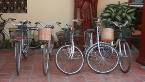 Trois vélos sont garés sur une terrasse carrelée, et chaque vélo est muni d'un panier en osier fixé au guidon.