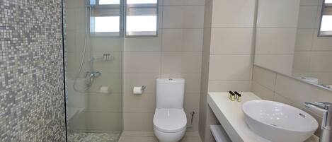 A bathroom with a toilet, a shower, and a sink.