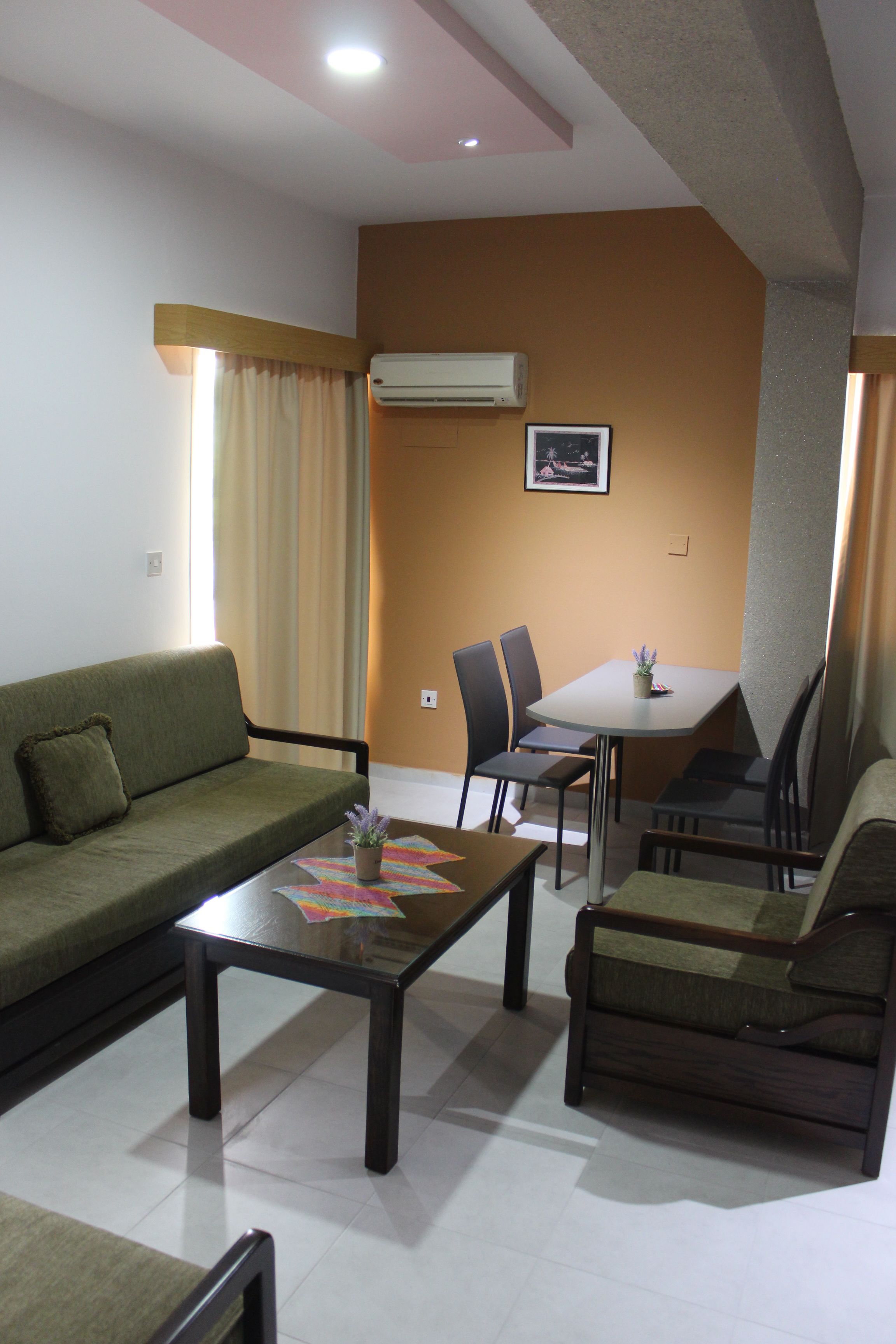 A living room with a sofa, a coffee table, and a dining table with chairs.