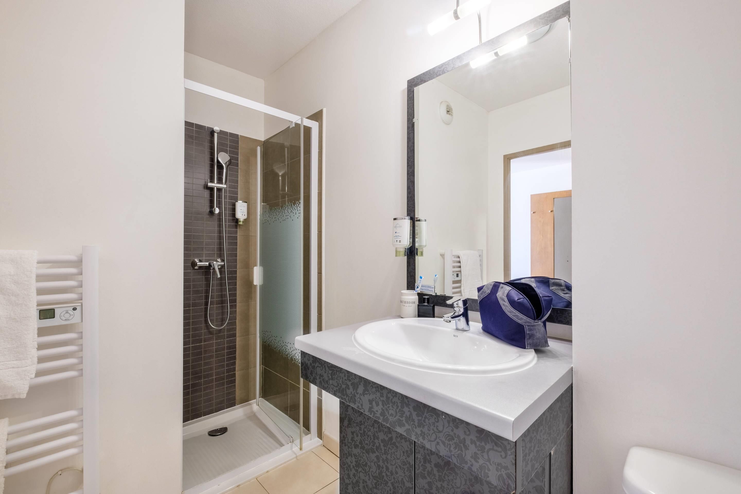A modern bathroom with a glass-enclosed shower, a white sink, and a large mirror.