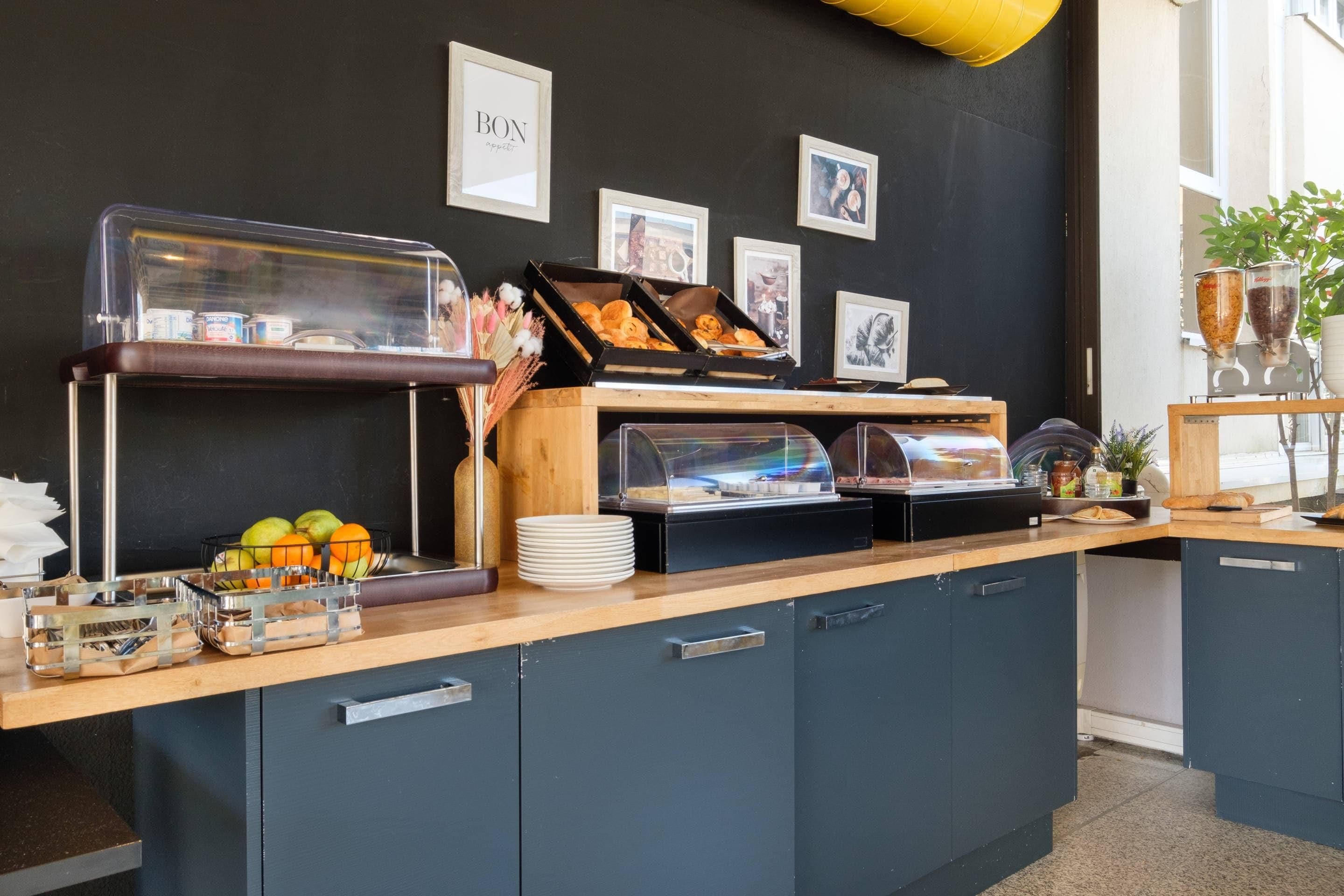 Un comptoir de buffet proposant divers plats, un saladier rempli de fruits et un espace dédié au café.