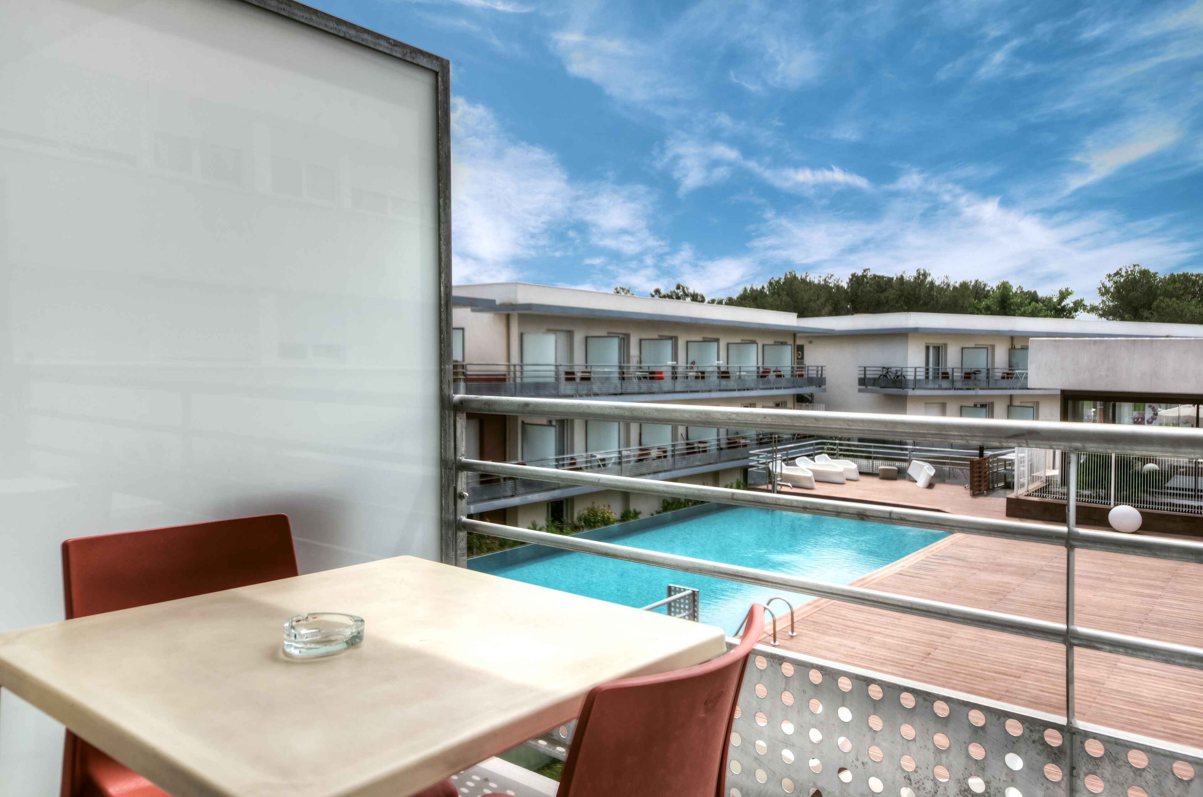 A balcony with a pool, a table, and chairs.