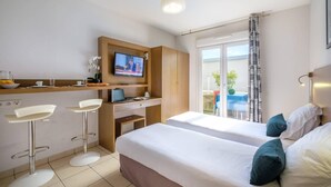 Hotellihuone, jossa on kaksi sänkyä, työpöytä tietokoneella, televisio ja parveke, jolta on näkymä.
