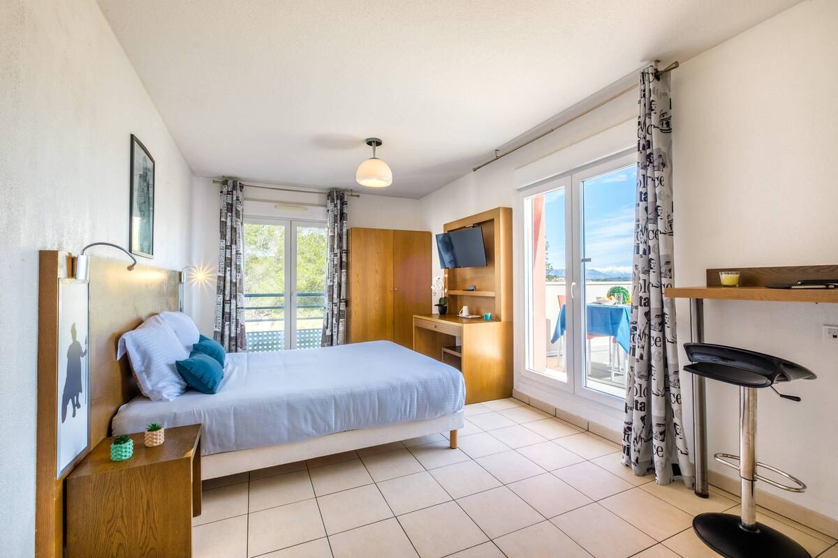 A bedroom with a bed, a TV, a desk, and a chair.