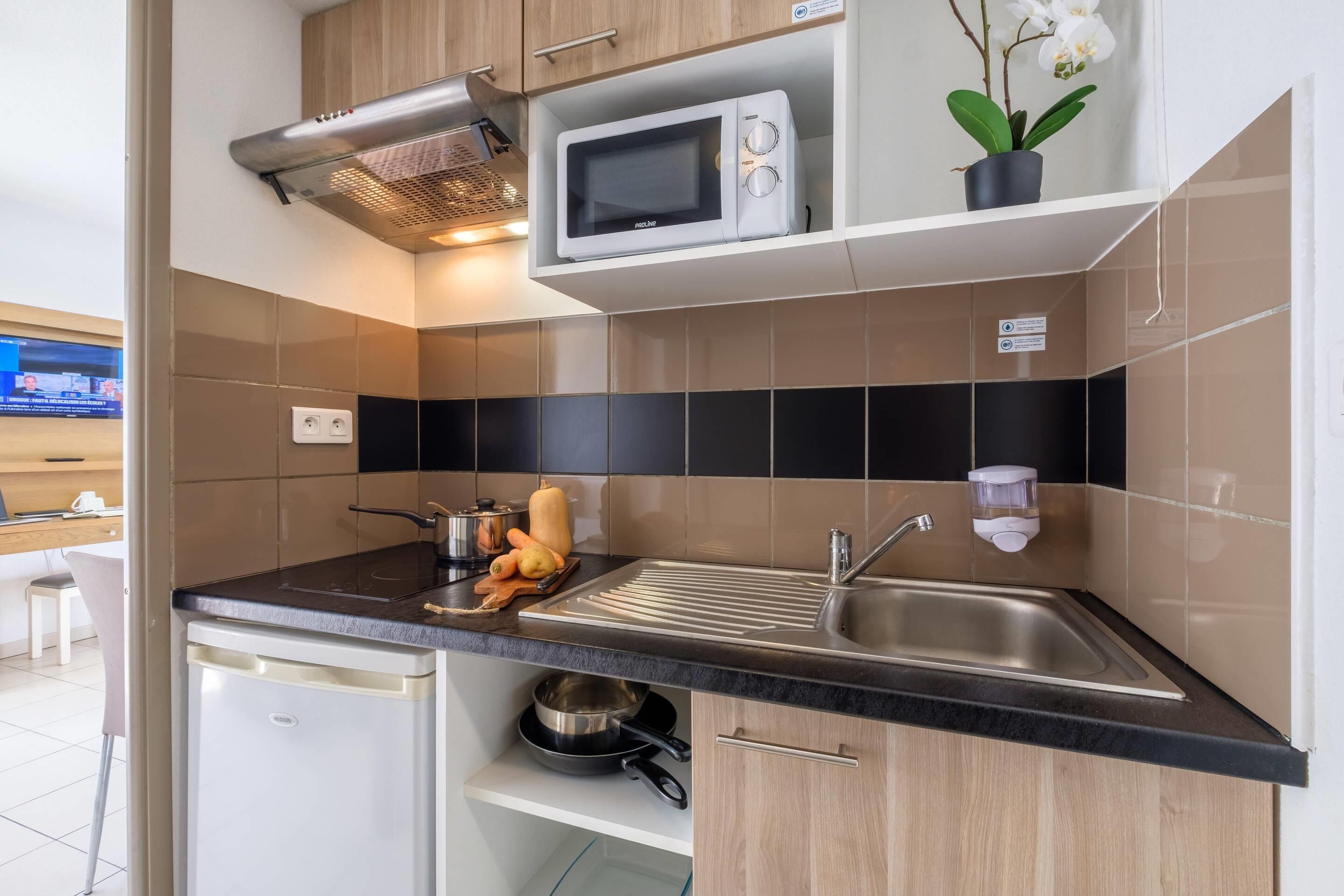A modern kitchen with a microwave, sink, and a small refrigerator.