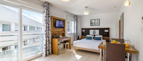 Habitación de hotel con cama, escritorio y balcón.