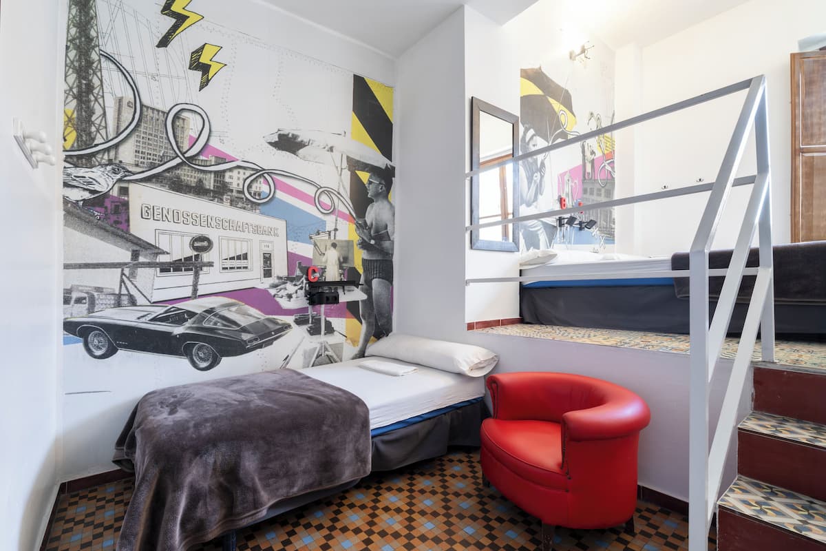 A room with a bed, a red chair, a window, and a wall mural.