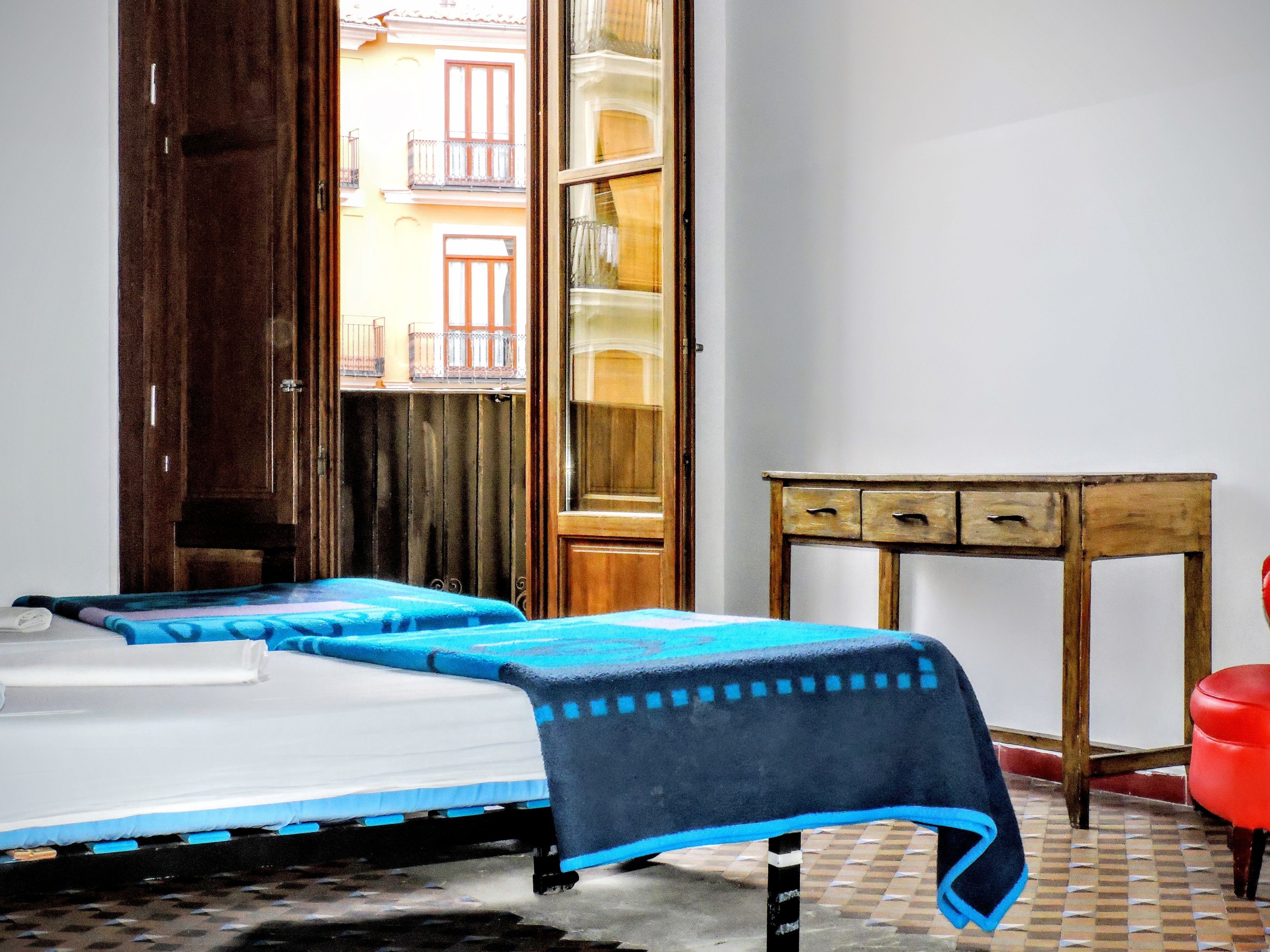 A room with a bed, a wooden table, and a red chair.
