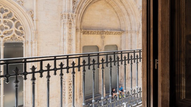 Uitzicht vanaf een balkon met decoratief stenen muurwerk en een versierd vloertapijt.