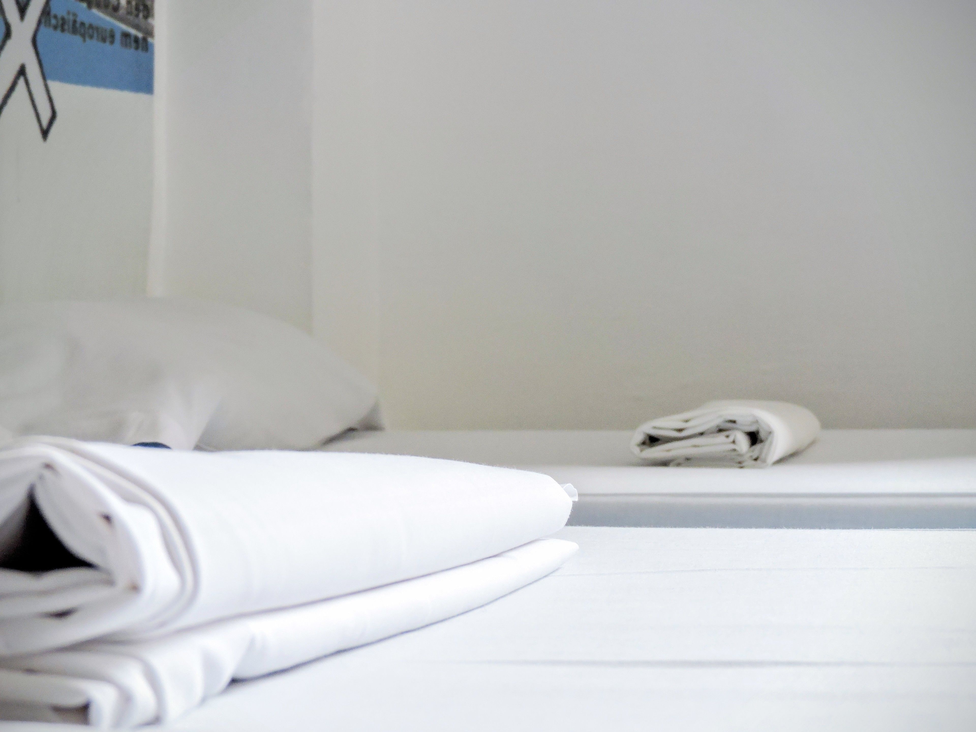 Un lit bien fait, avec du linge de lit blanc et un oreiller blanc.