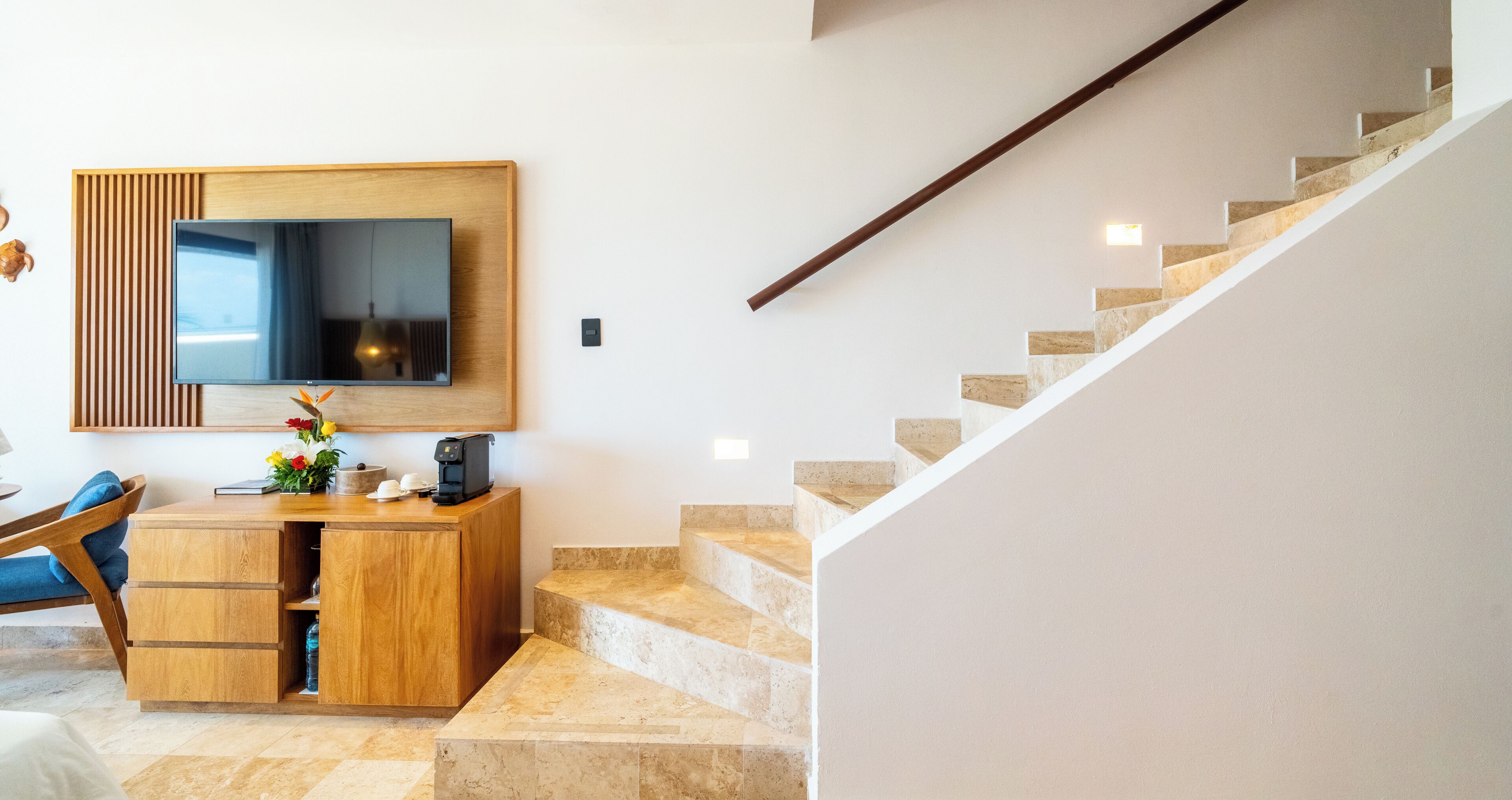 Un interior moderno con un escritorio de madera, un televisor de pantalla plana y una escalera.