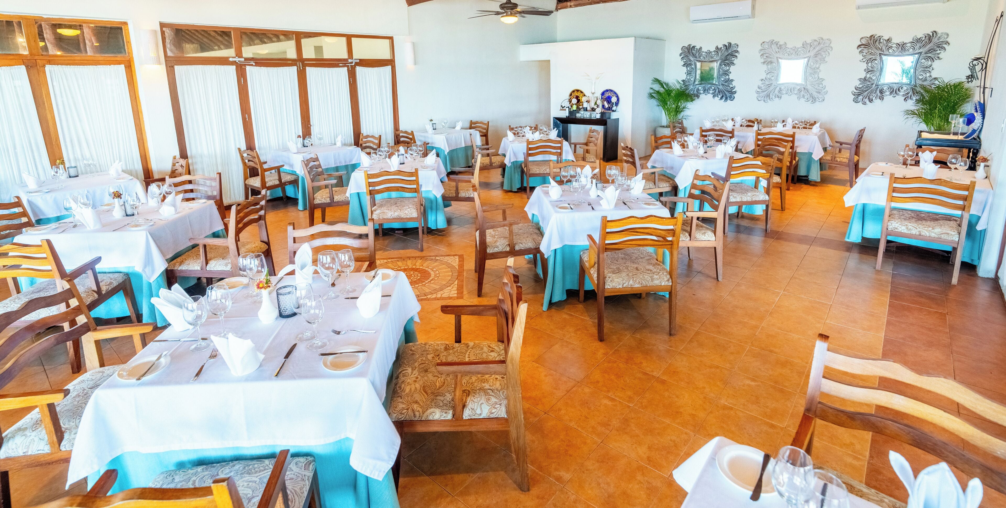 Een restaurant met meerdere tafels, stoelen en een betegelde vloer.