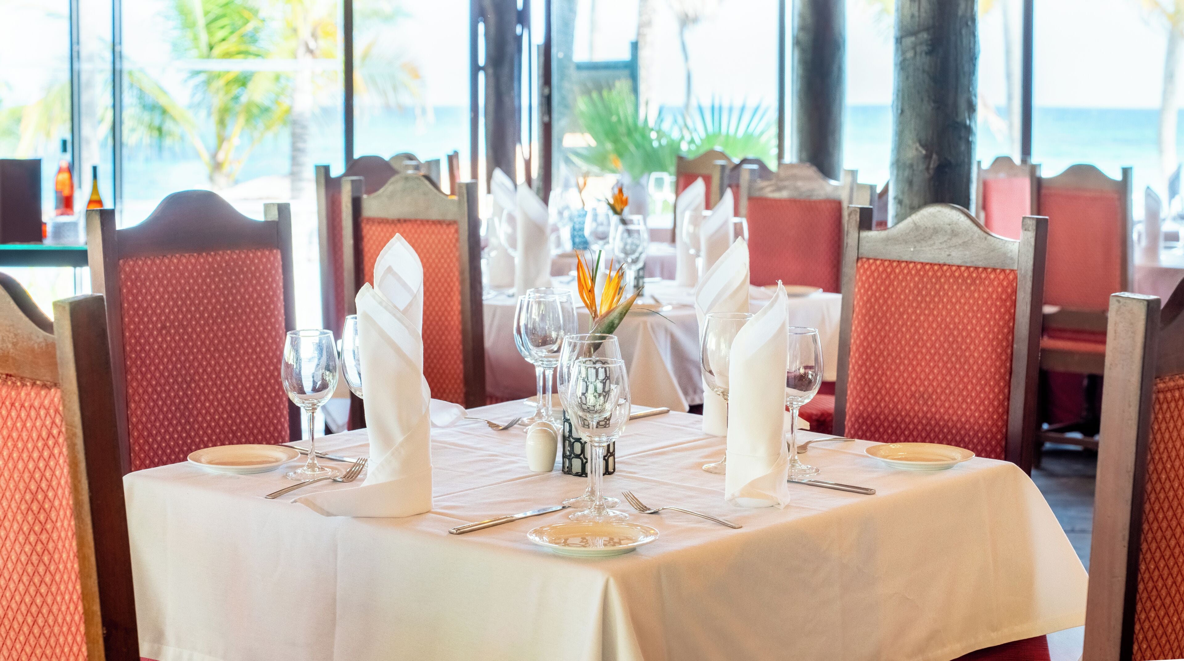 Une table à manger dressée pour quatre personnes, avec une nappe blanche, de la verrerie et des serviettes pliées.