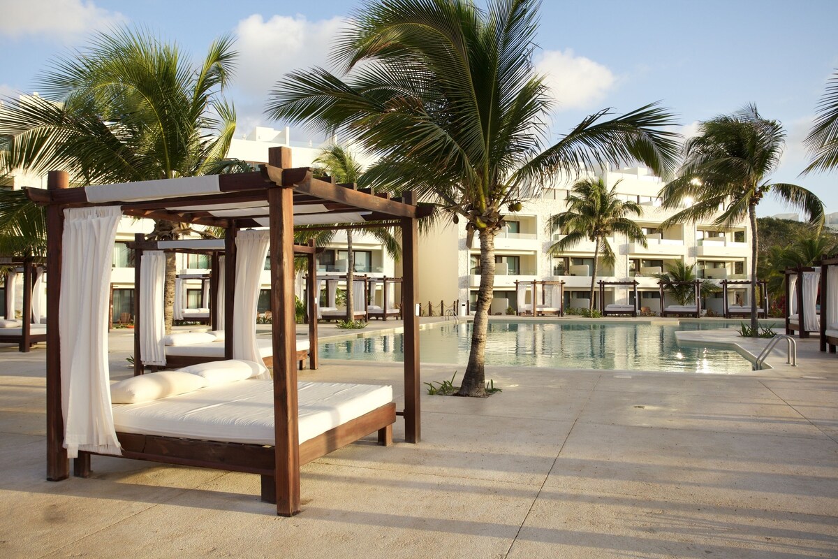 Akumal Bay Beach & Wellness Resort pool area with large sun loungers