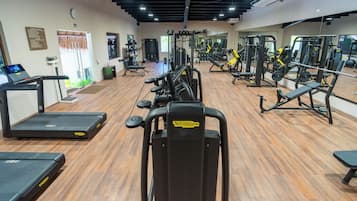 A gym with cardio machines, weightlifting equipment, and mirrors.