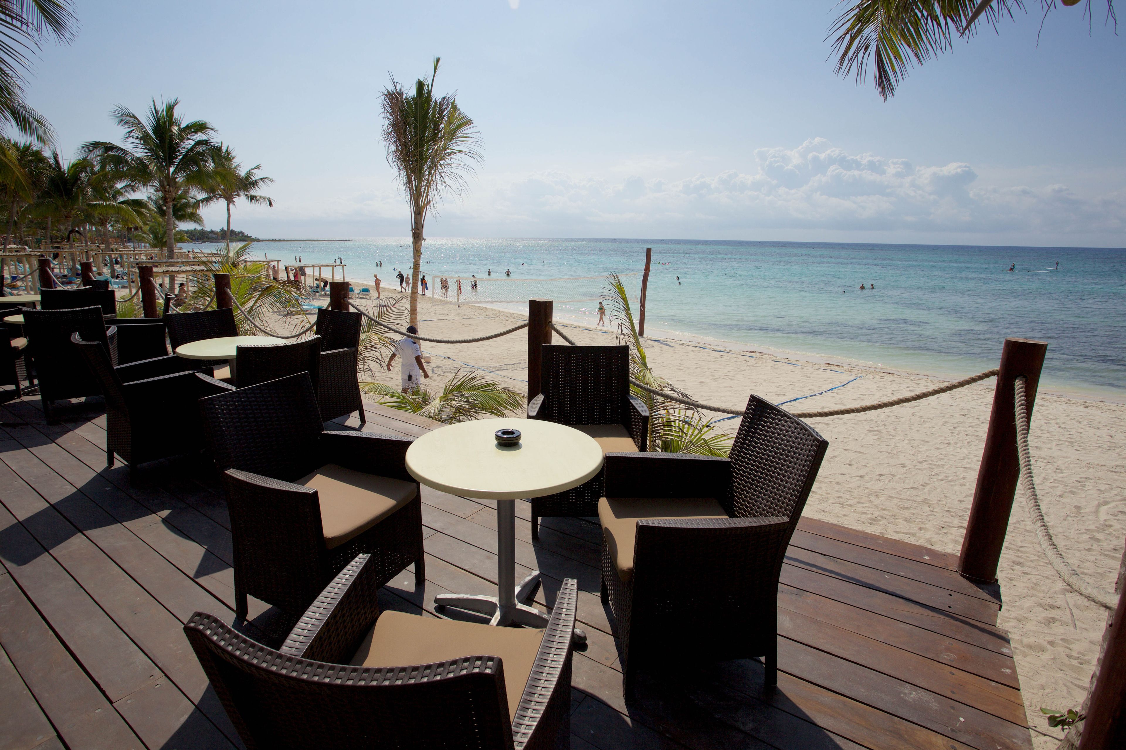 A beachside patio with wicker furniture and a view of the ocean.