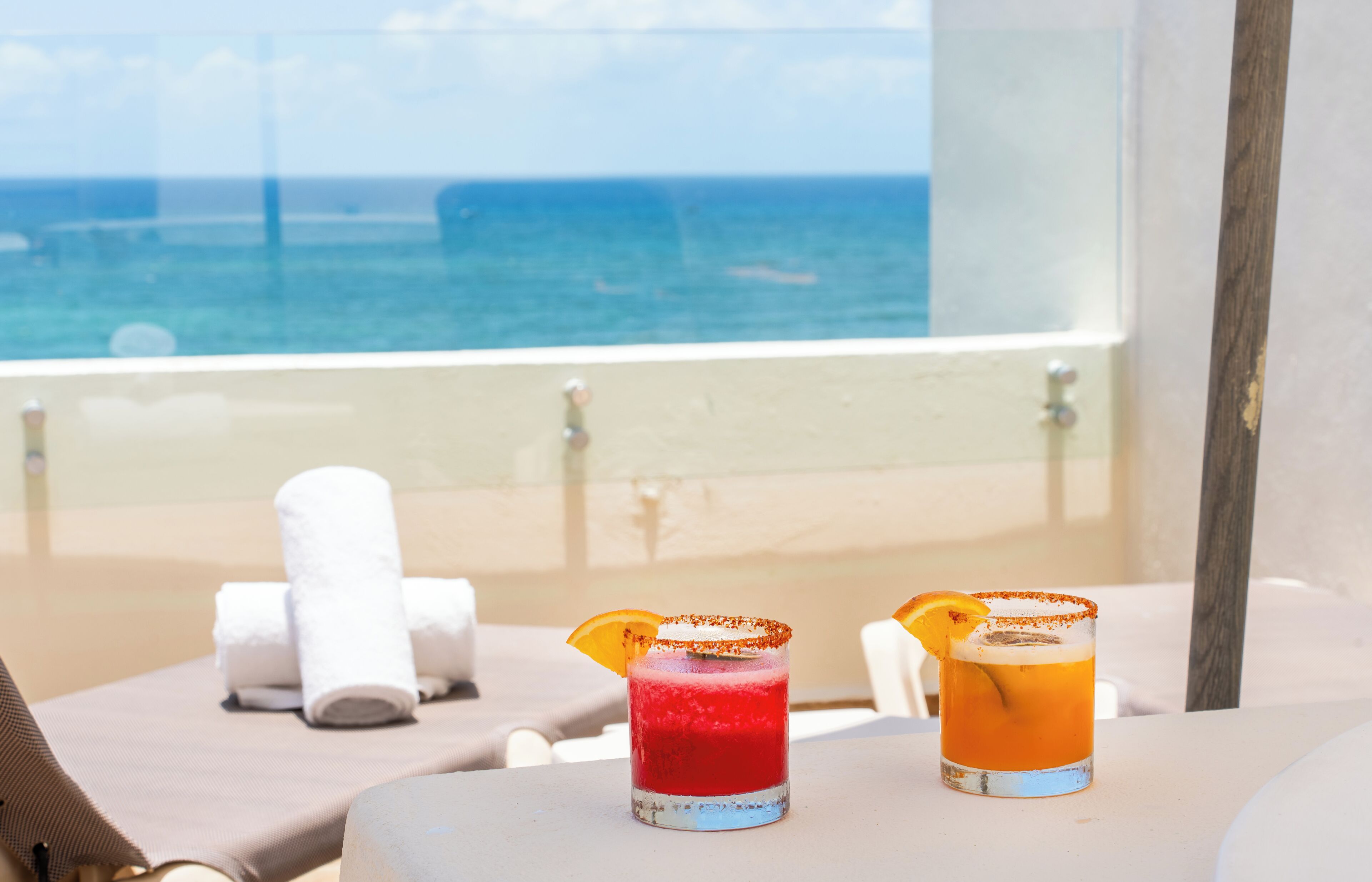 Two cocktails on a table with a view of the ocean.