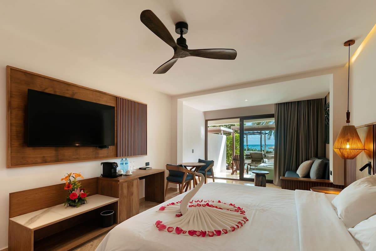 Habitación de hotel con cama, escritorio, televisor y vista al océano.