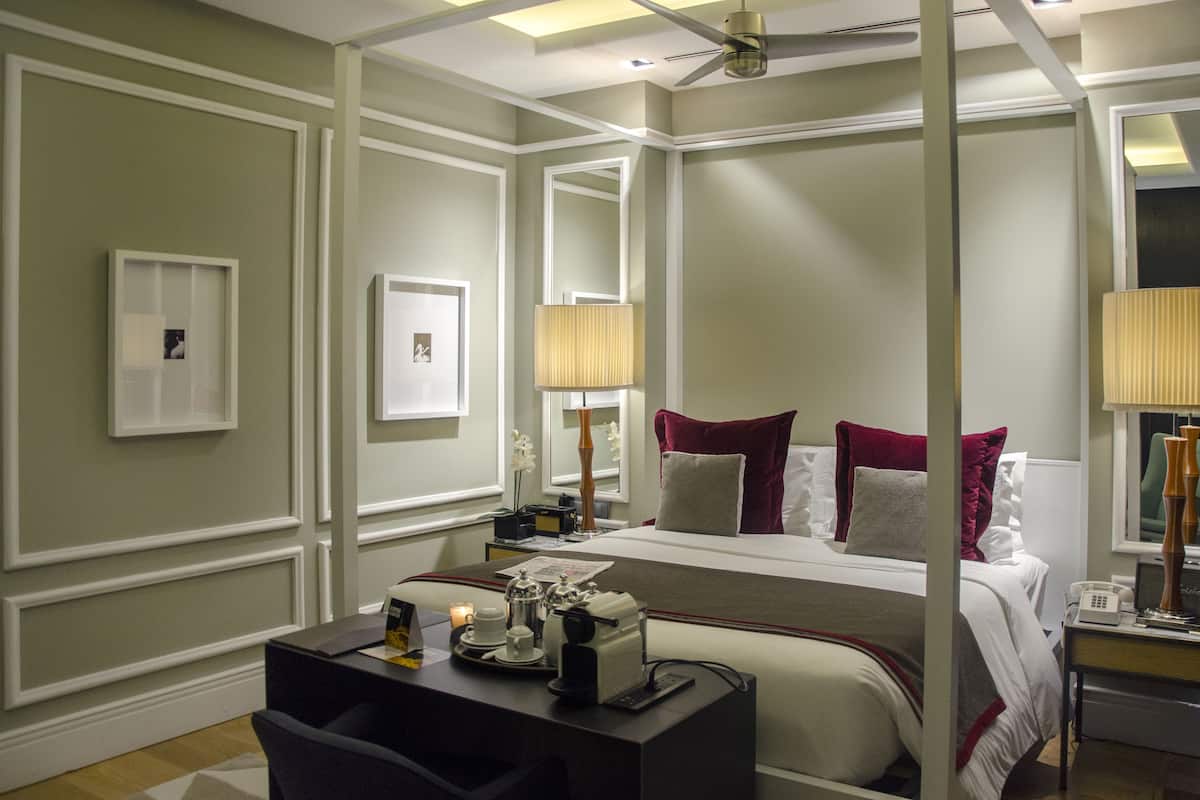 Una habitación de hotel con una cama grande, un escritorio con lámpara y un espejo.