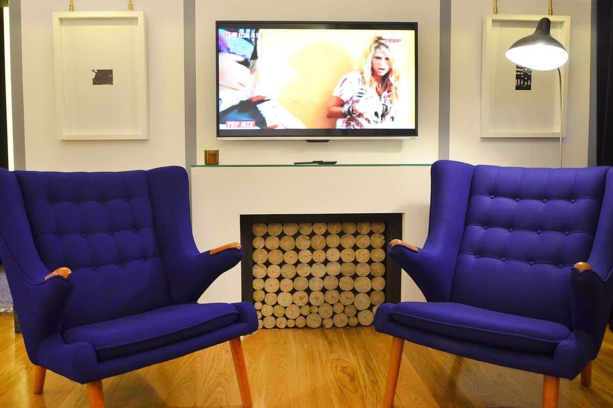 Dos sillones azules orientados hacia un televisor montado en la pared.