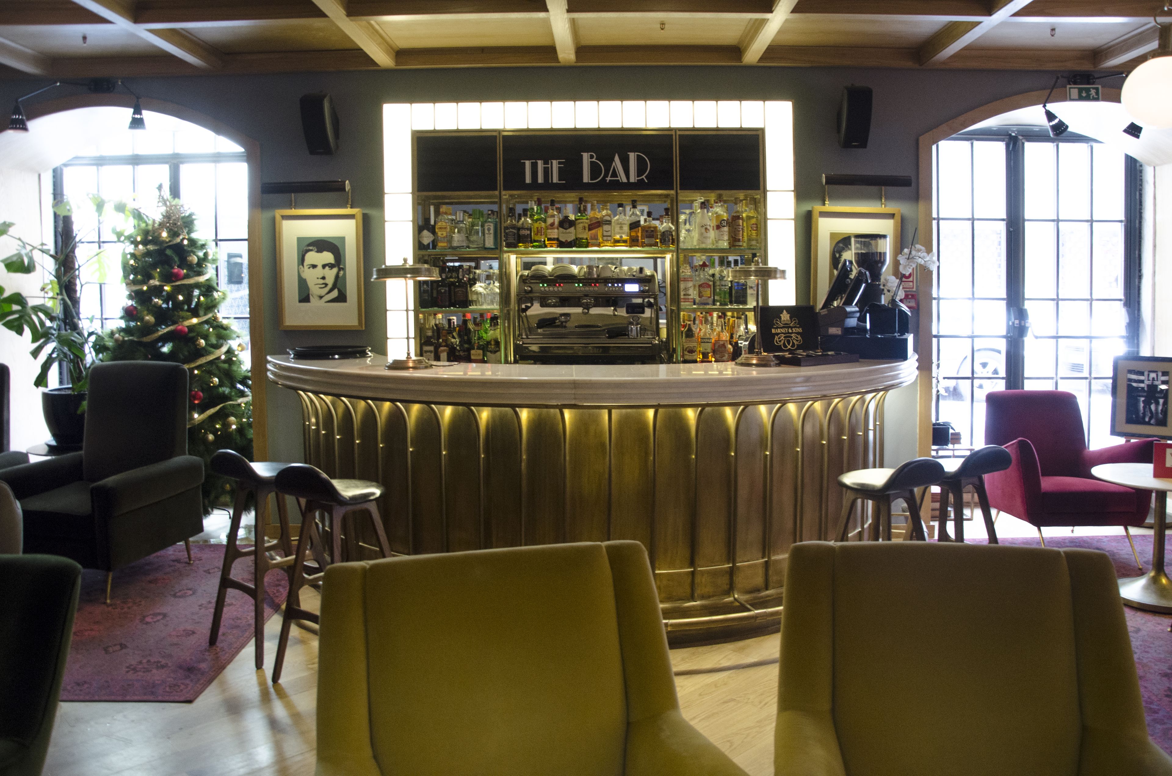 A bar area with a counter, chairs, a Christmas tree, and framed pictures on the walls.