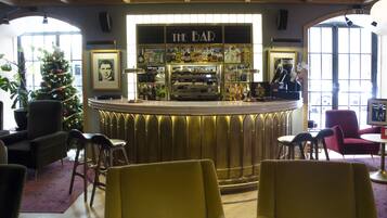 A bar area with a counter, chairs, a Christmas tree, and framed pictures on the walls.