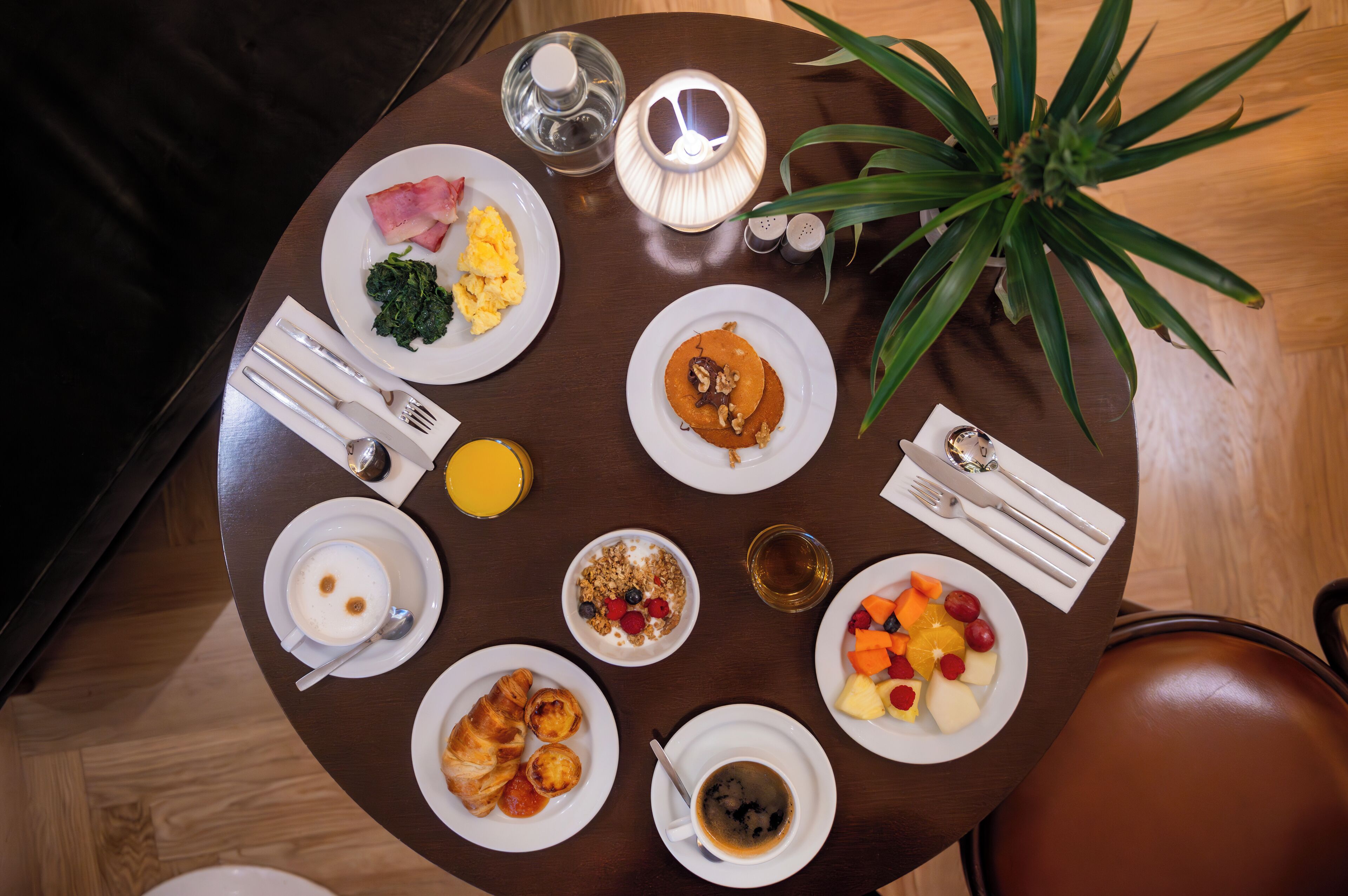 Een ronde eettafel met borden vol ontbijt, zoals eieren, toast en fruit.