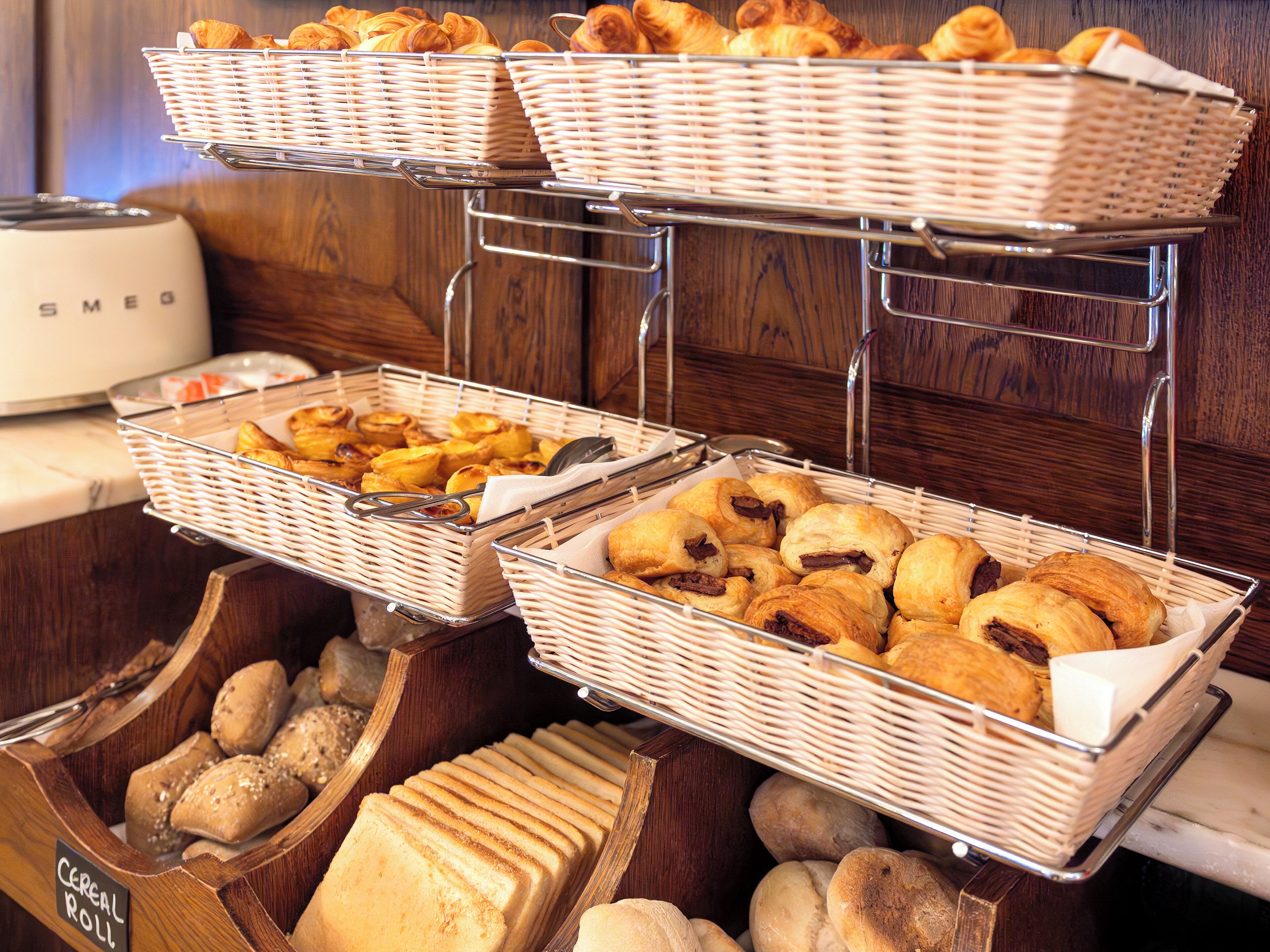 A buffet with various baked goods including bread, pastries, and rolls.