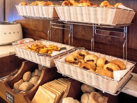 A buffet with various baked goods including bread, pastries, and rolls.
