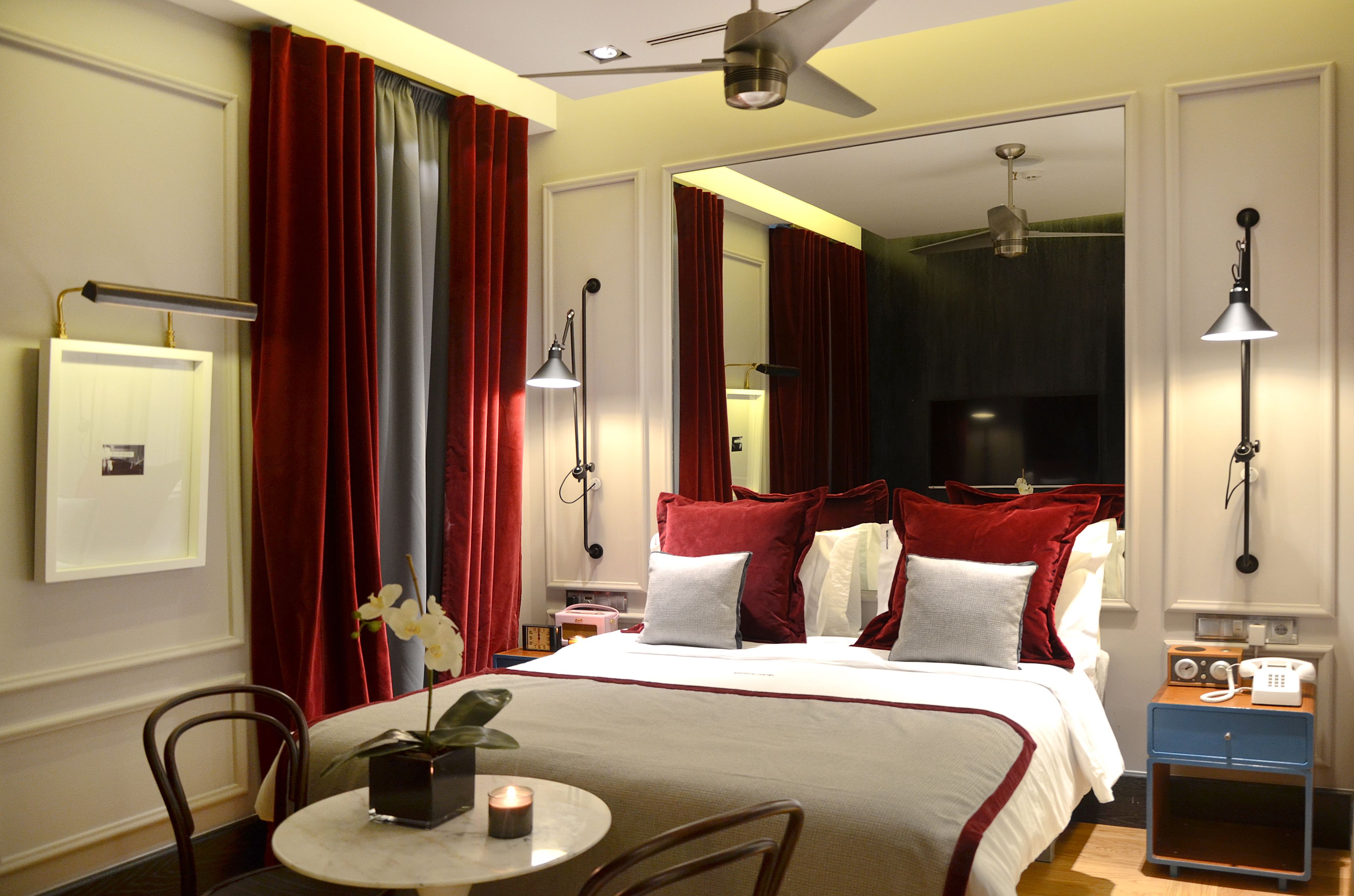 Una habitación de hotel con cama, mesita de noche, lámpara y teléfono.
