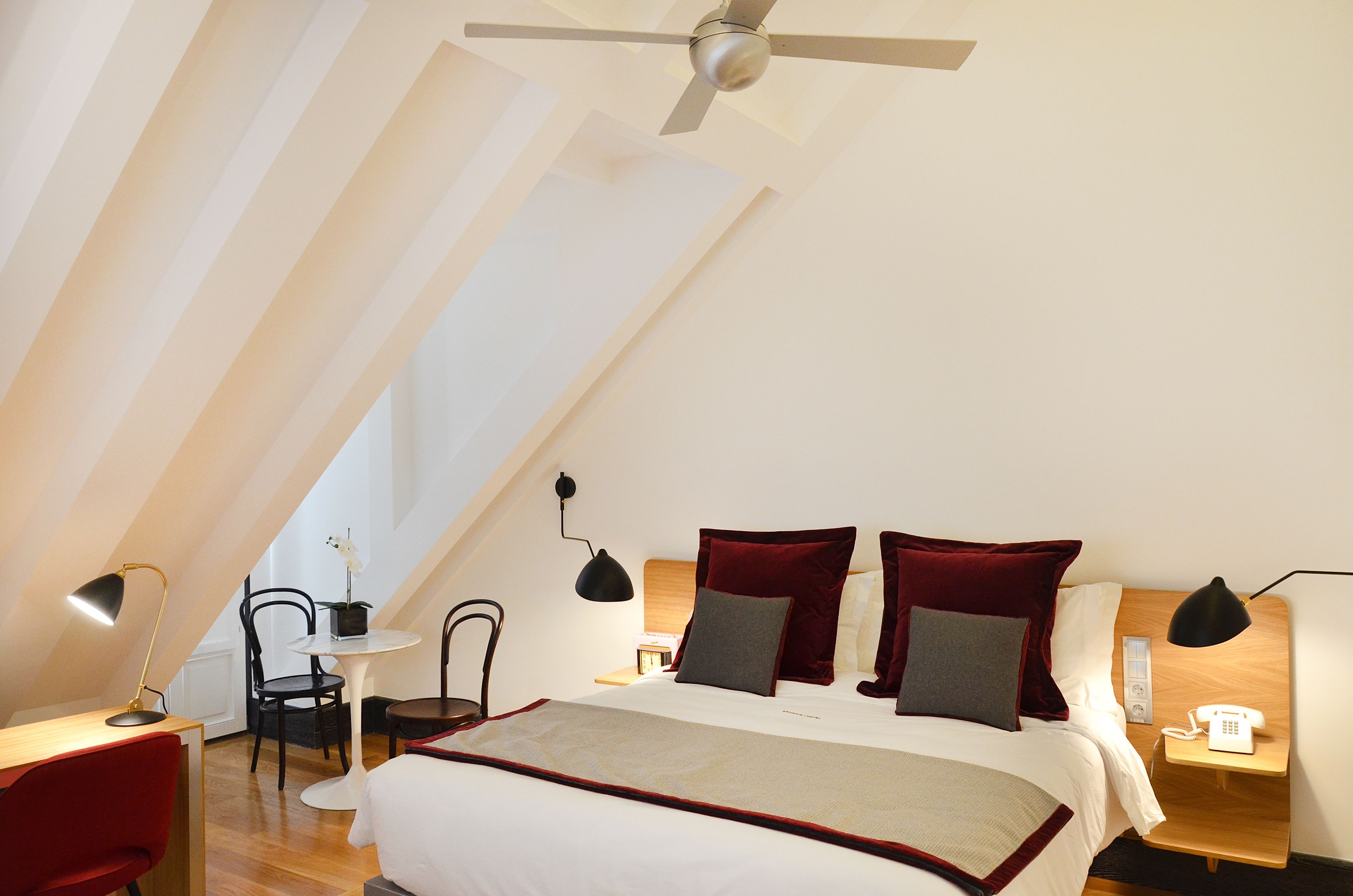 A bedroom with a bed, bedside tables, a desk, and chairs.