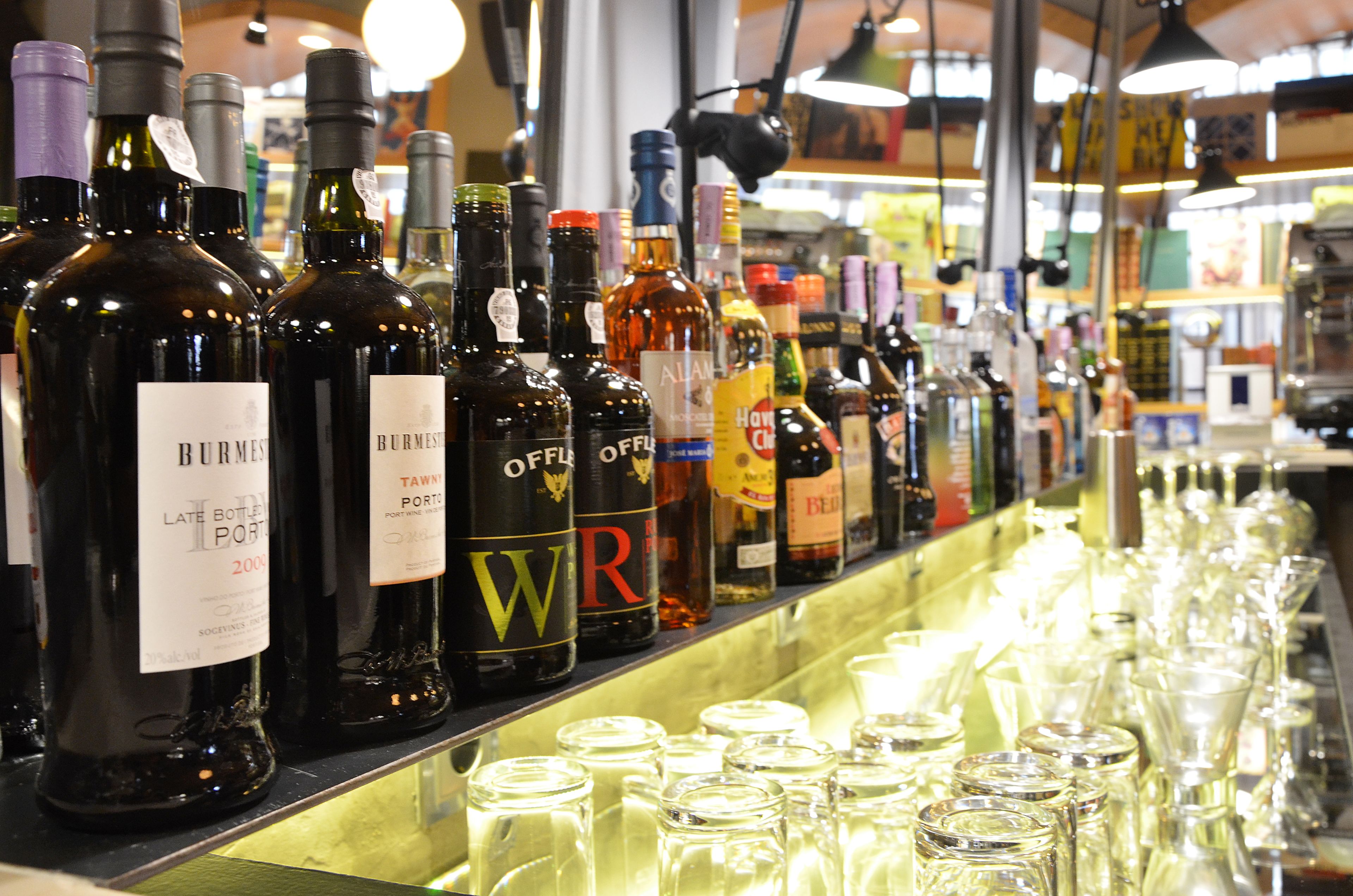 Una barra con diversas botellas de licor y vasos alineados.