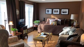 Una habitación de hotel acogedora con cama, televisor, escritorio con lámpara y sofá.