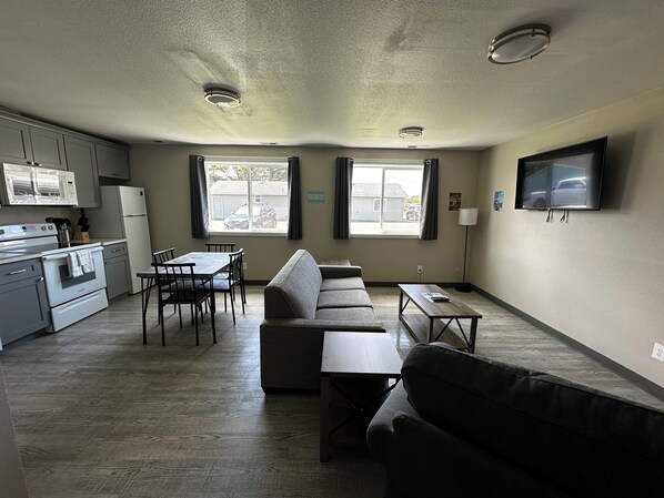 Un espacio habitable compacto con kitchenette, un sofá, una mesa de comedor y un televisor.
