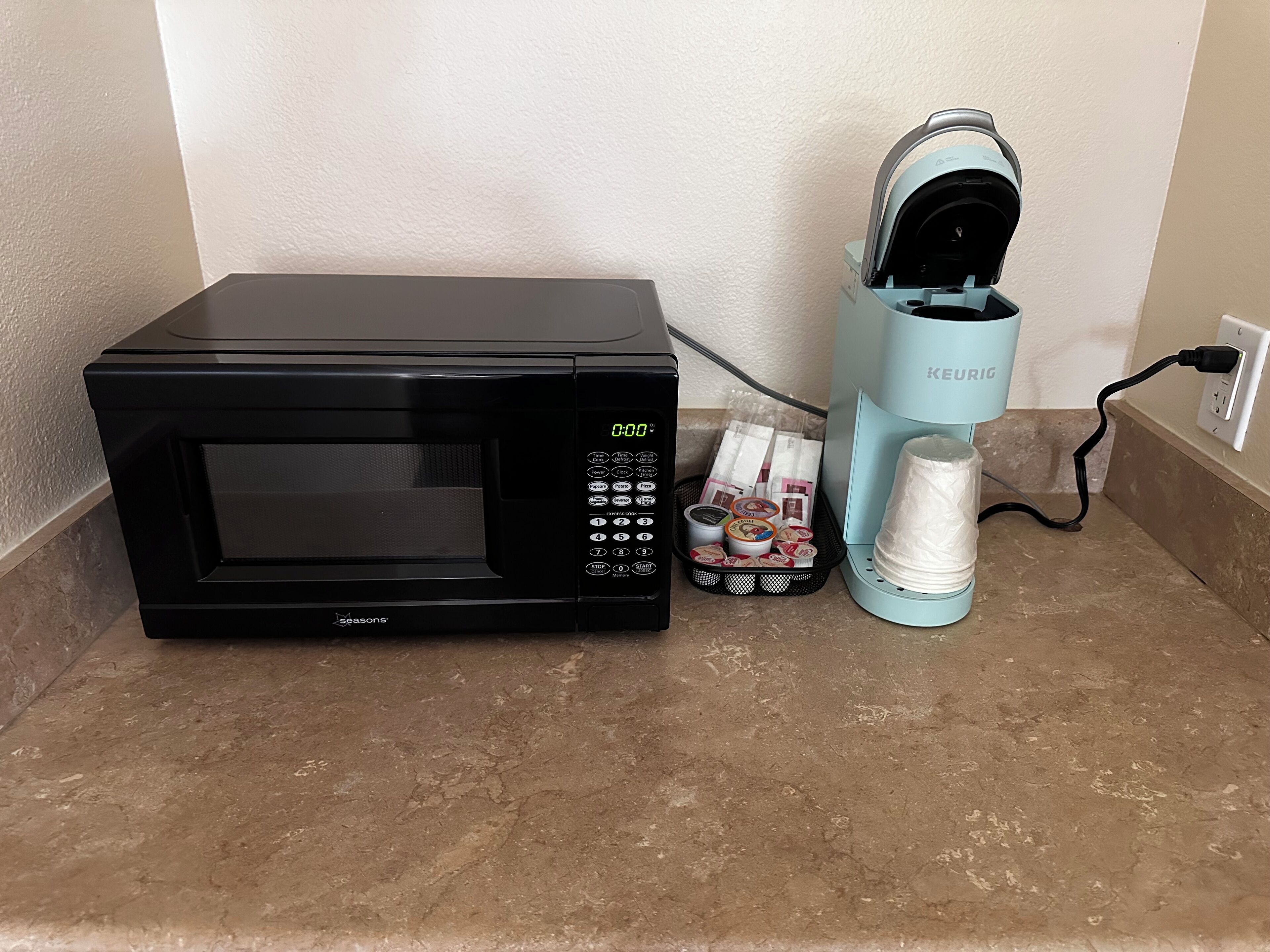 A black microwave and a Keurig coffee maker on a countertop.