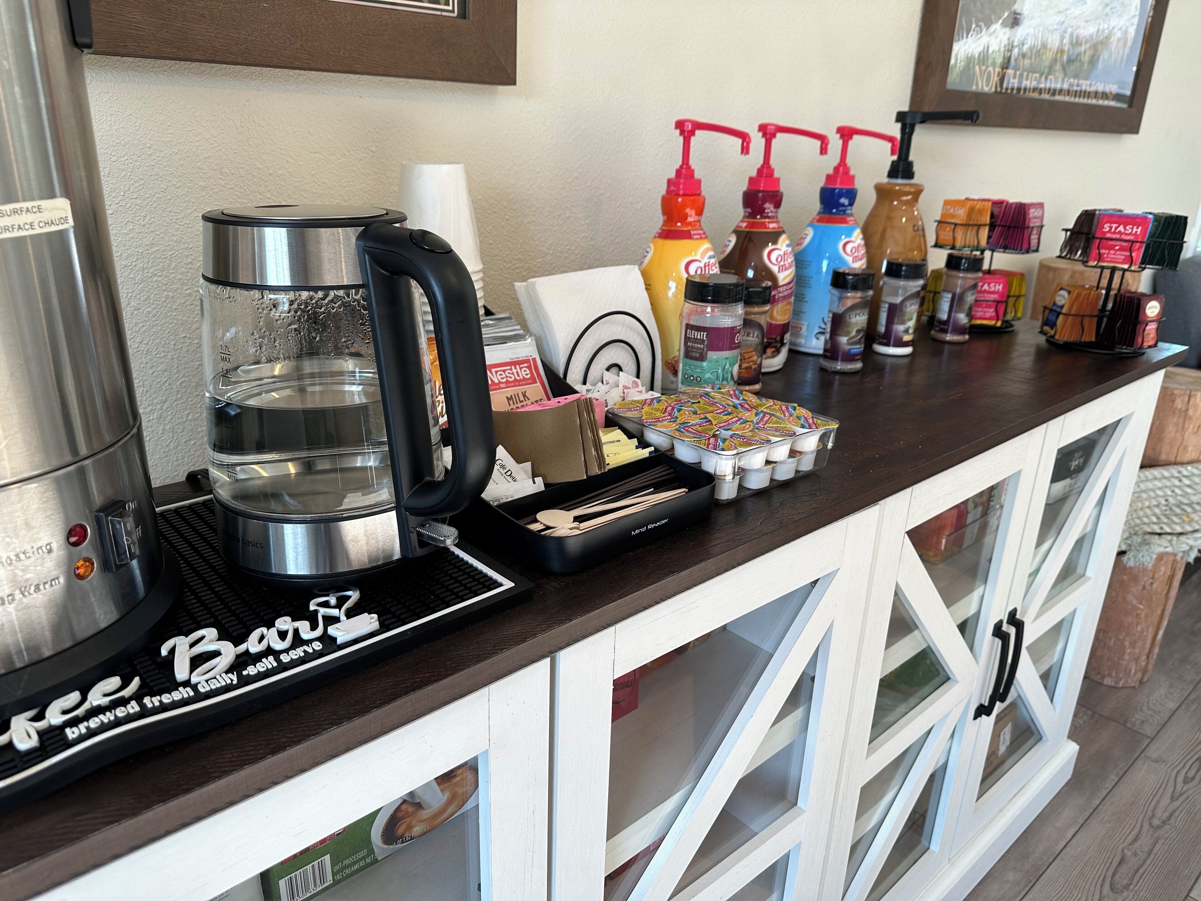 Una estación de café con cafetera, cartones de leche y cápsulas de café sobre una encimera.