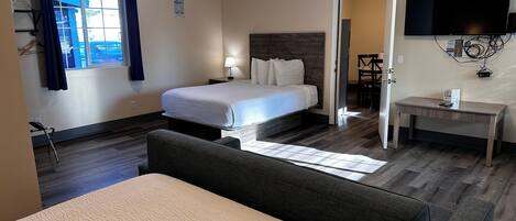 Une chambre d’hôtel comprenant un lit, une table de chevet, une lampe et un bureau avec une chaise.