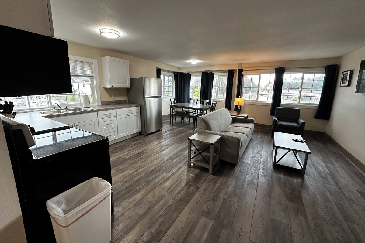 Un apartamento moderno con cocina, comedor y sala de estar. Cuenta con un ventanal grande, un refrigerador, un sofá y una mesa de comedor.
