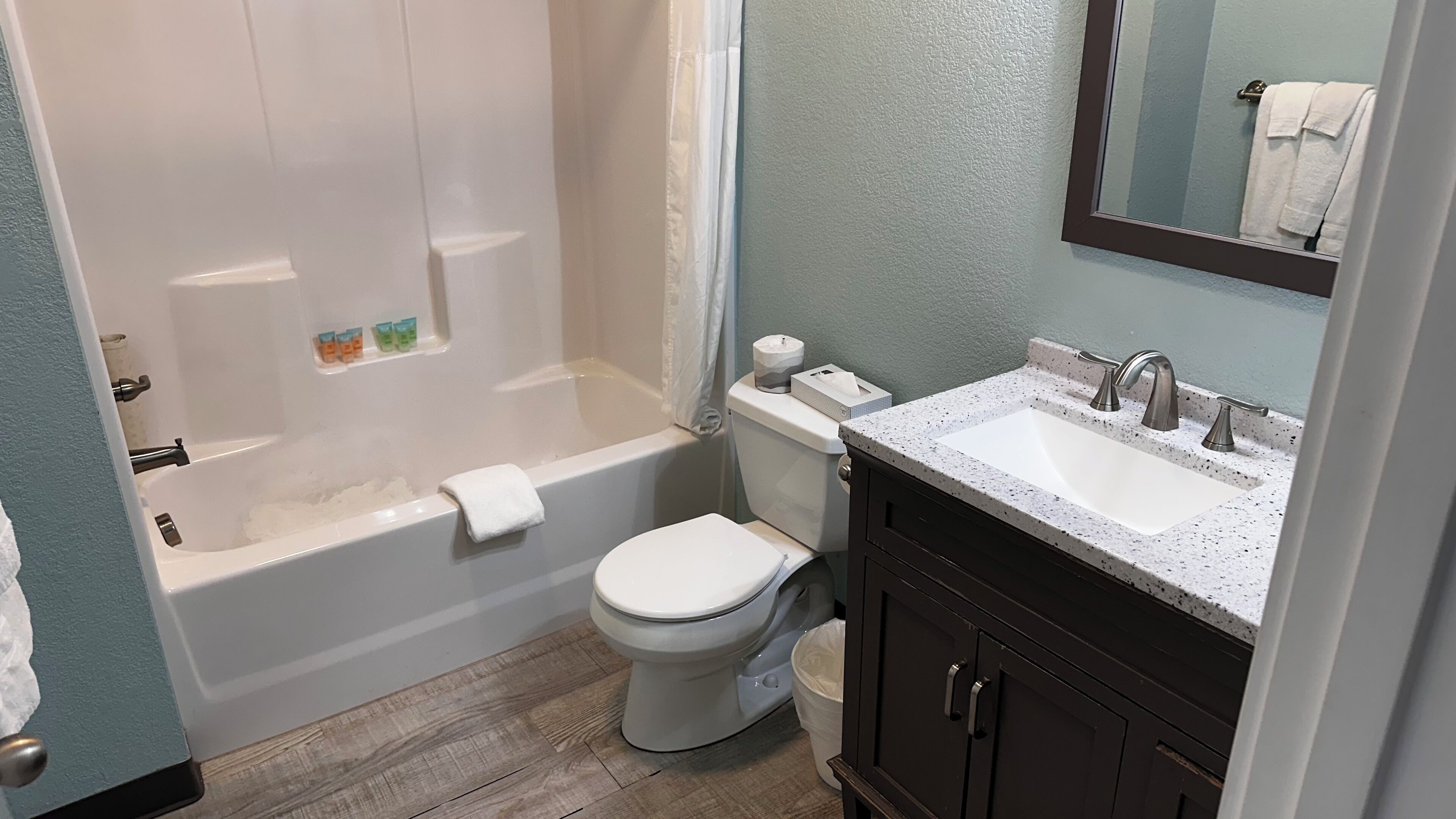 A bathroom with a bathtub, toilet, sink, and mirror.