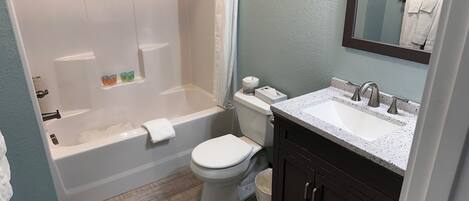 A bathroom with a bathtub, toilet, sink, and mirror.