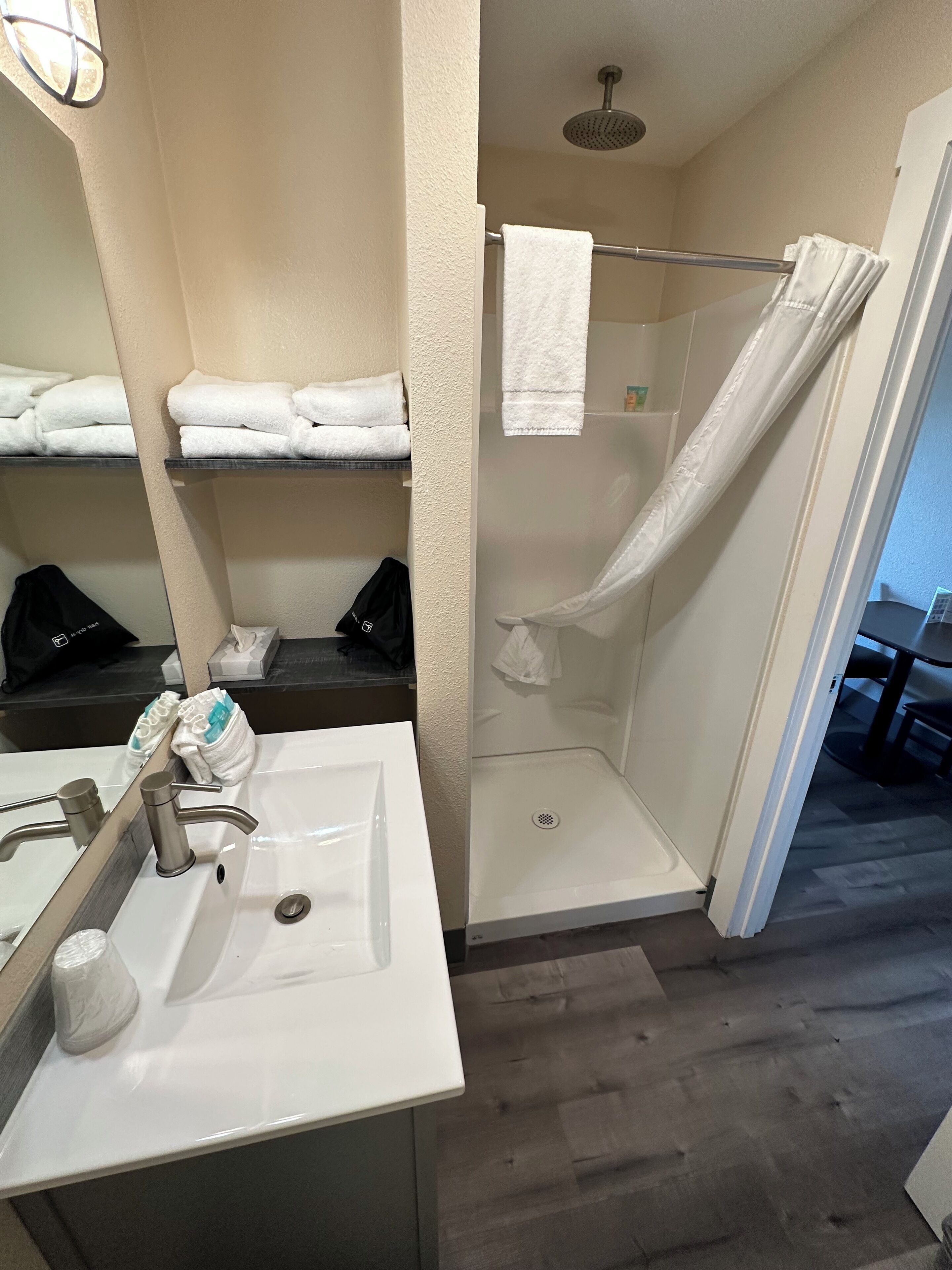 Ein Badezimmer mit Waschbecken, Handtuchhalter, Dusche und Spiegel.