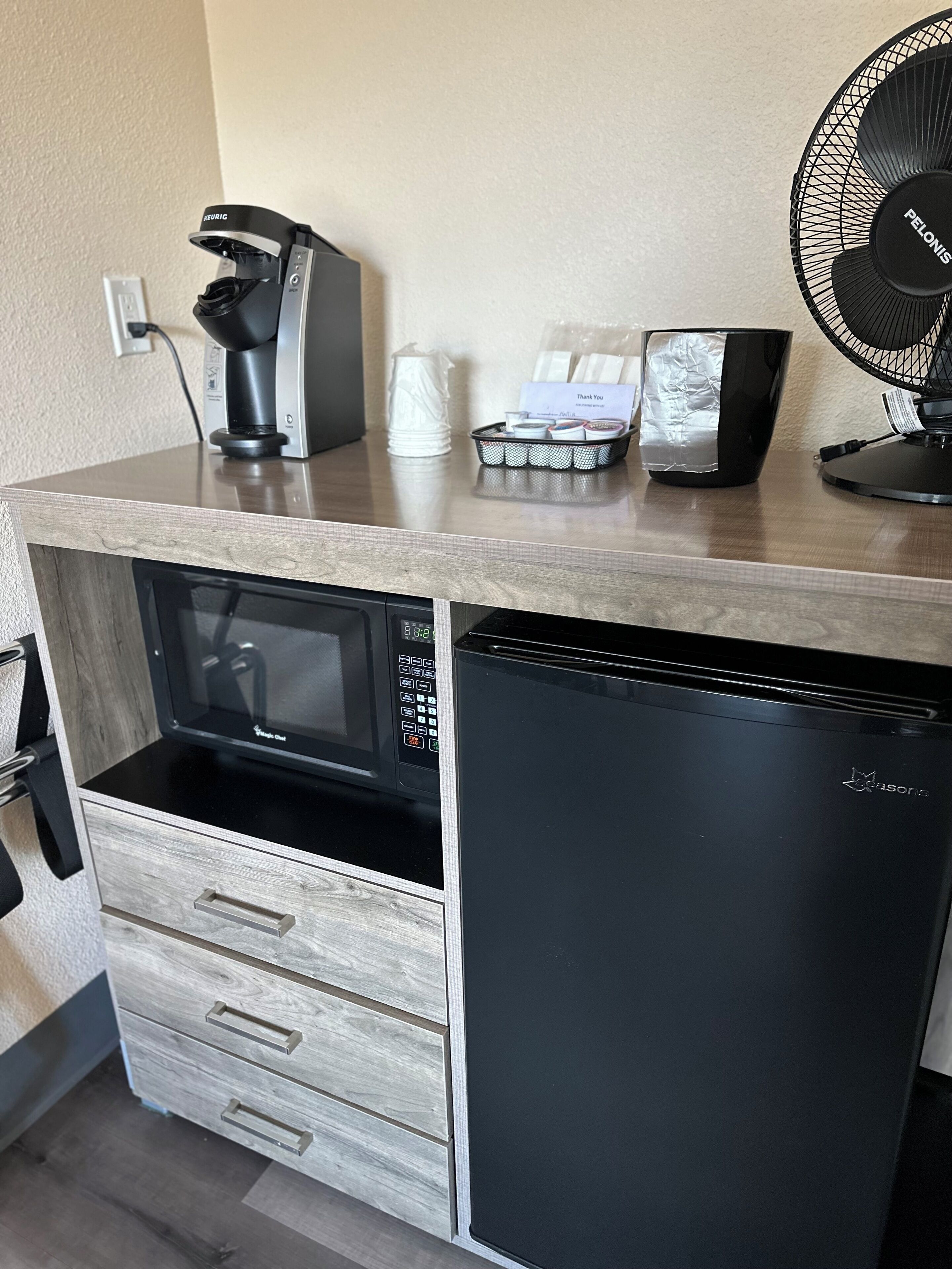 Uma cozinha compacta equipada com micro-ondas, cafeteira e frigorífico.