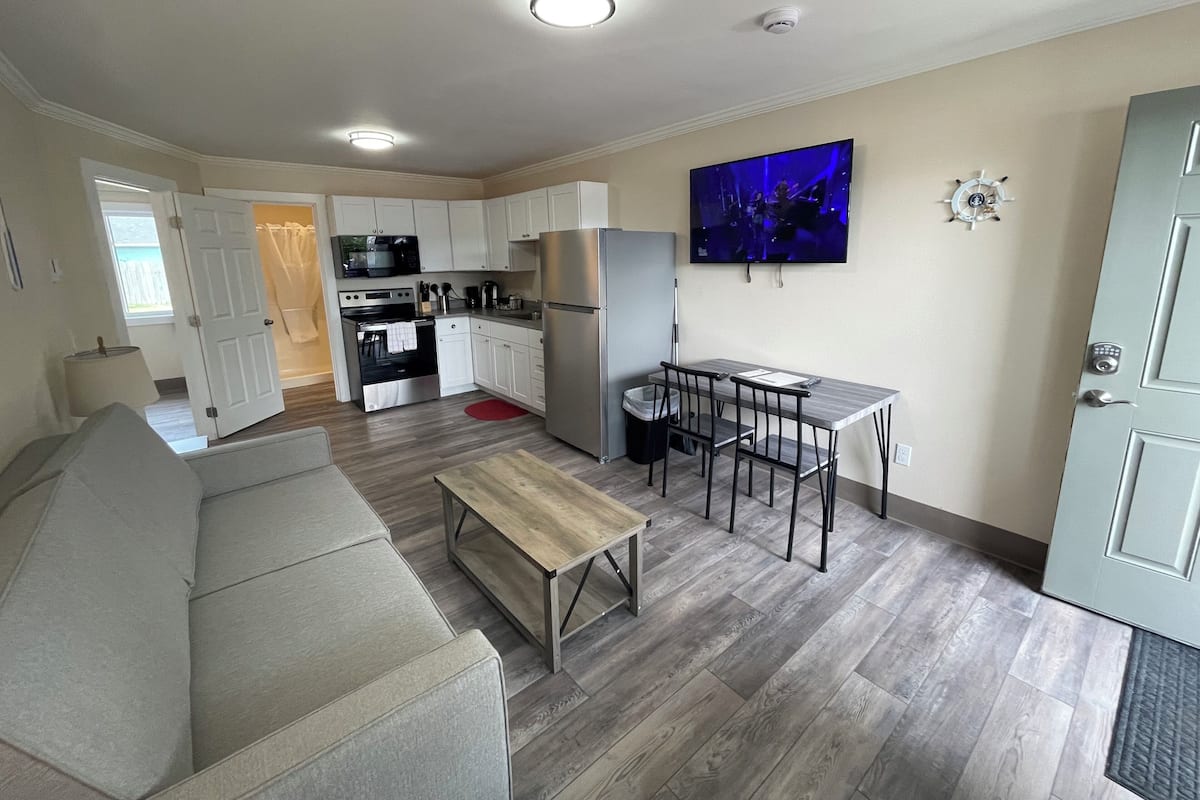 Un espacio habitable compacto con kitchenette, comedor y zona de estar.