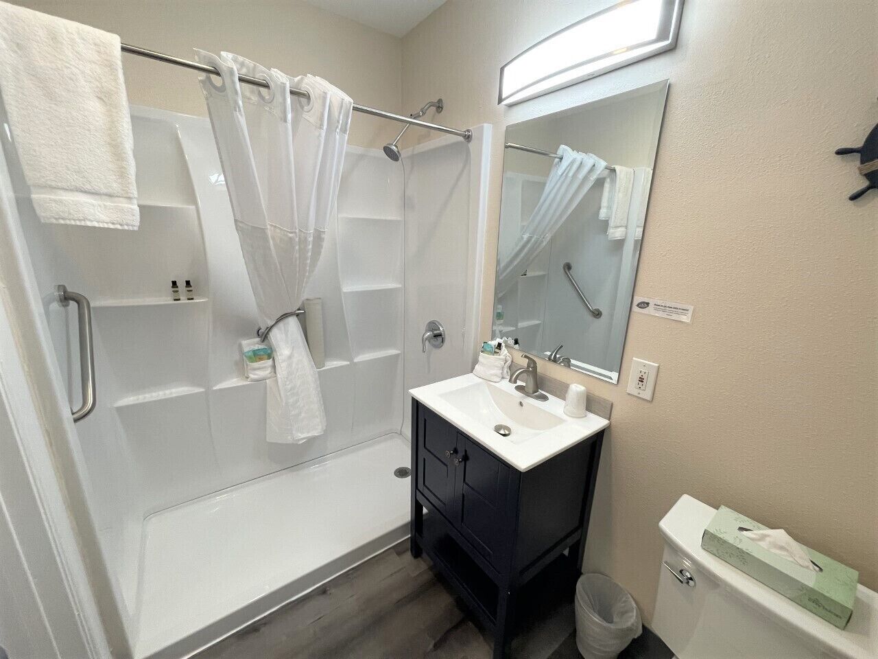 A bathroom with a shower, a sink, a mirror, and a toilet.