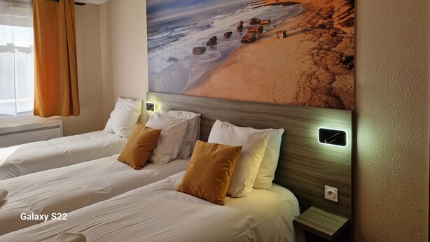 Habitación de hotel con dos camas, un mural de playa y una lámpara colgante moderna.