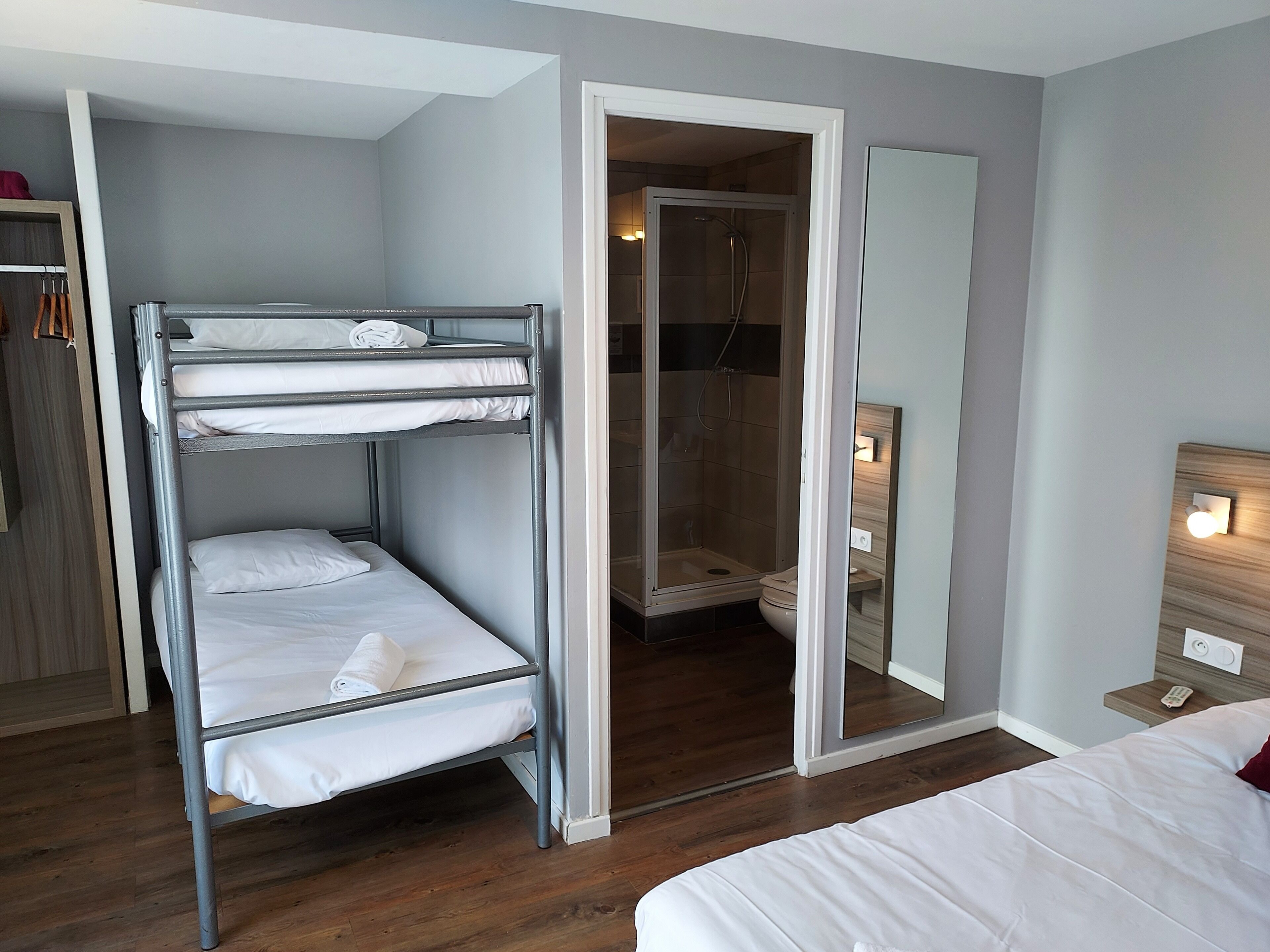 Een slaapkamer met stapelbed, douche en spiegel.