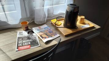 Une table avec une machine à café, une tasse, un magazine et un plateau sur lequel se trouvent un sac et un paquet.