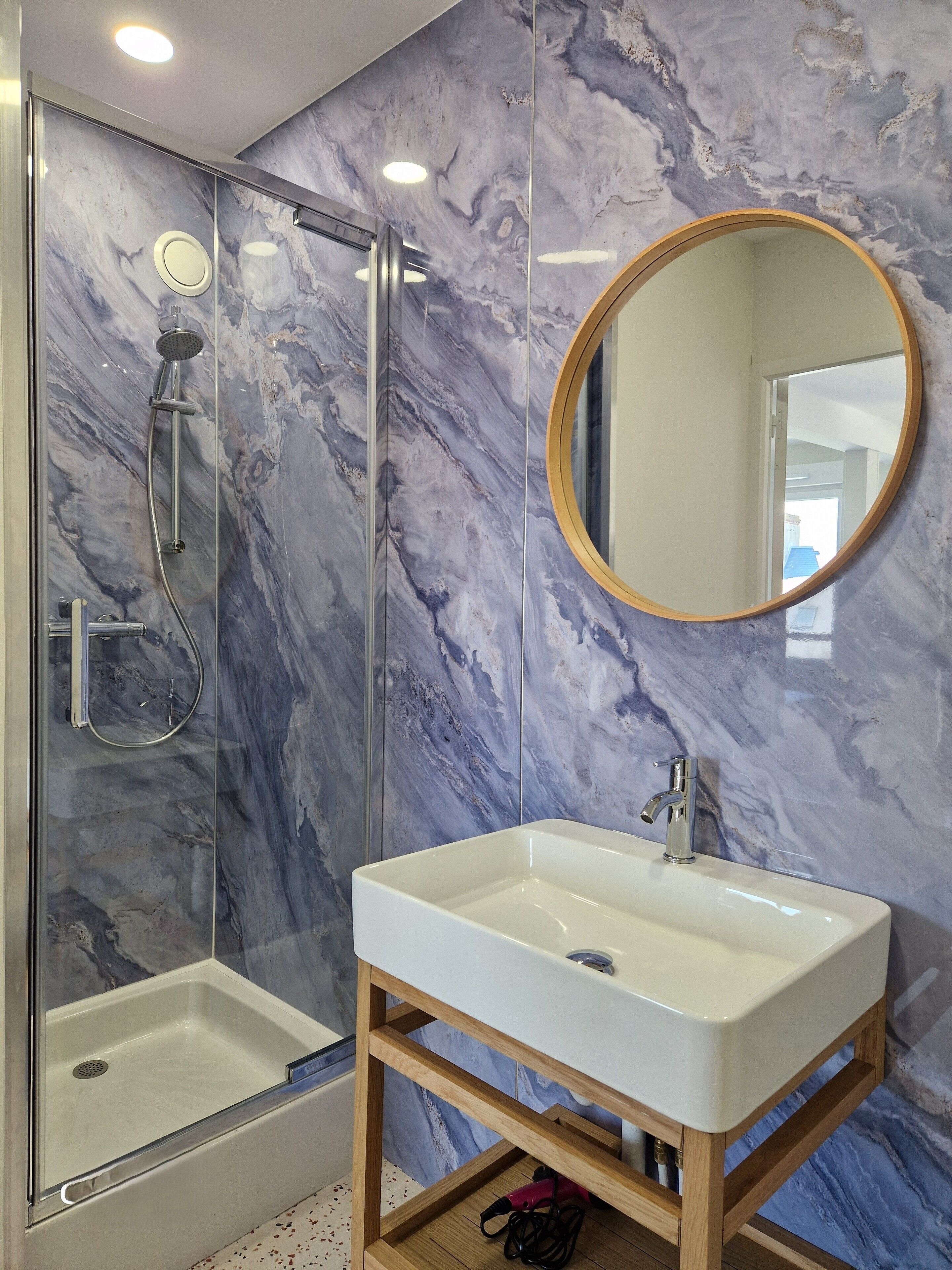 Ein Badezimmer mit Dusche, Waschbecken und Spiegel.