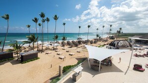 A beach resort with palm trees, lounge areas, and a pool.