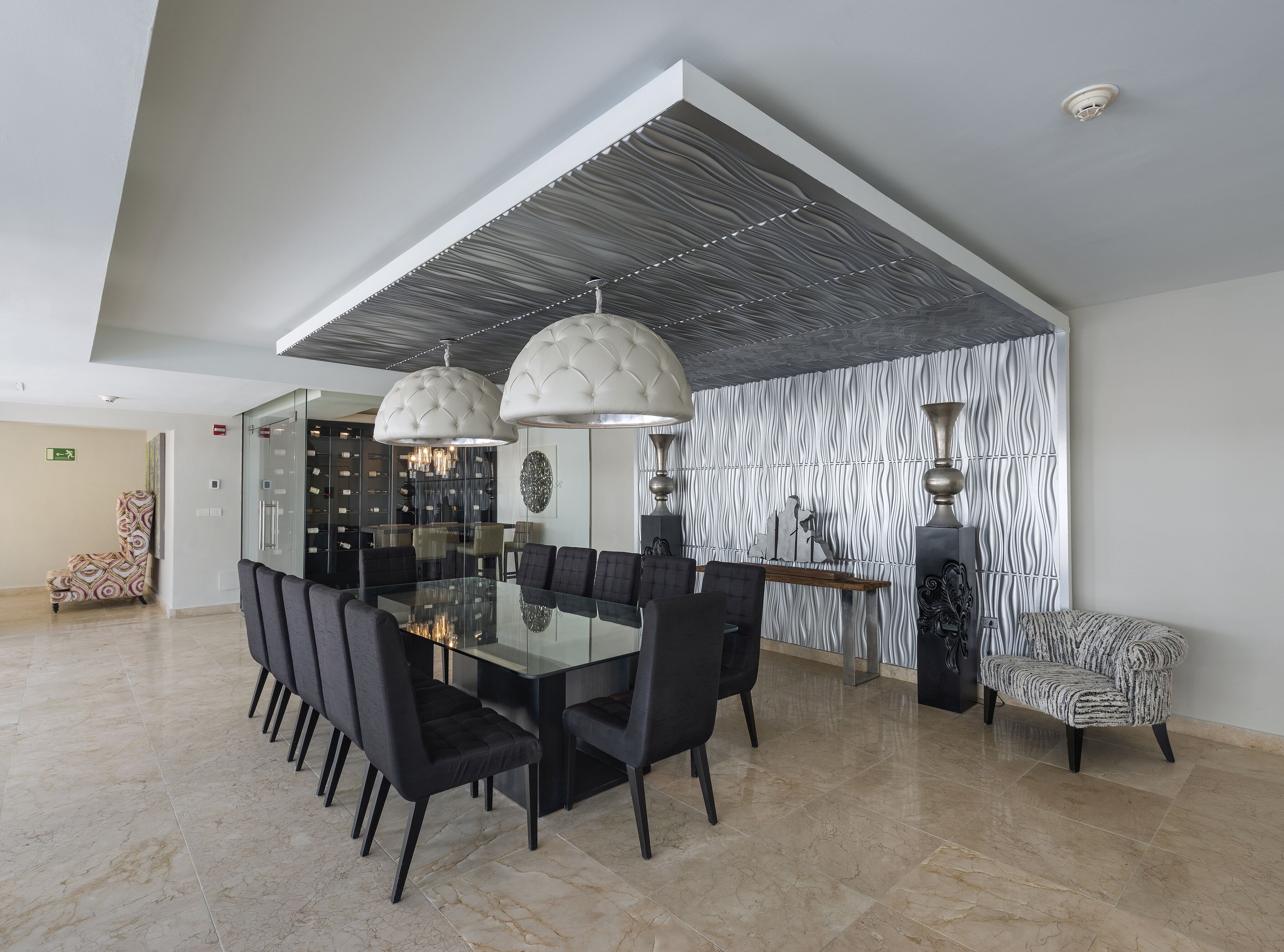 Un espace repas moderne avec une table en verre, des chaises noires et des luminaires suspendus.